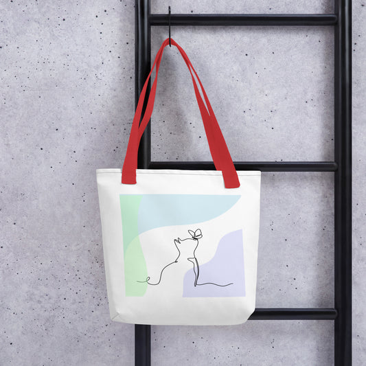 Front View of a tote bag with a design of a cat and butterfly outline. Red Handle.