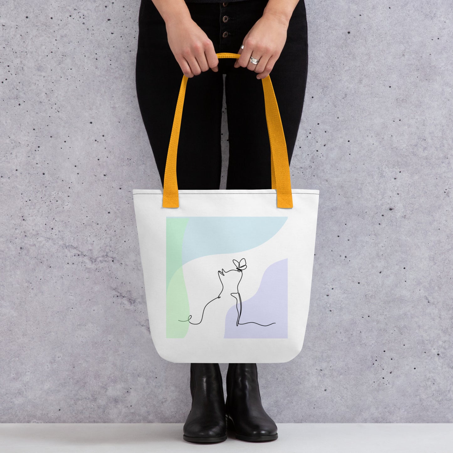 Front View of a tote bag with a design of a cat and butterfly outline. Yellow Handle.
