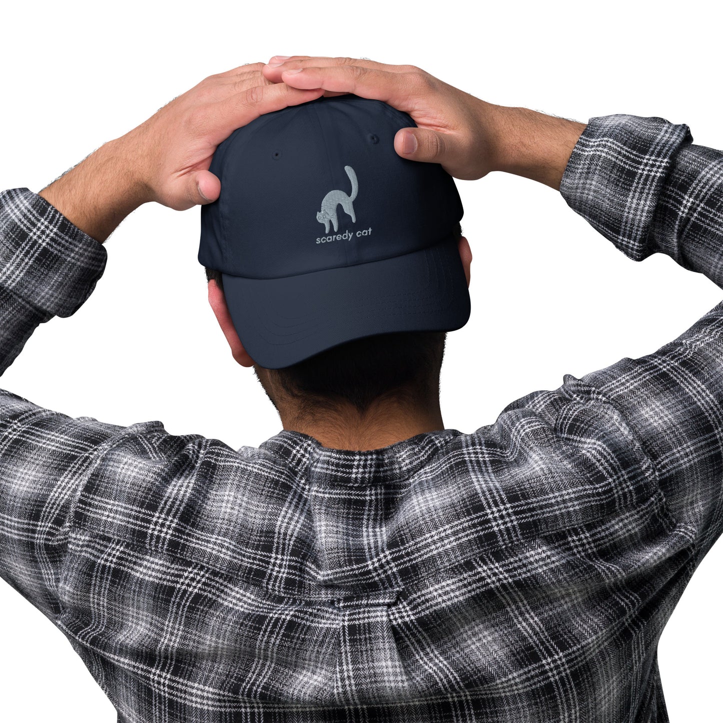 Man wearing a navy cap with a design of a scared cat with the words "Scaredy Cat".