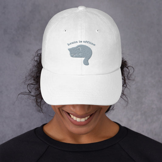 Woman wearing a white cap with a design of a cat hiding its face and the words 'Brain is Offline'.