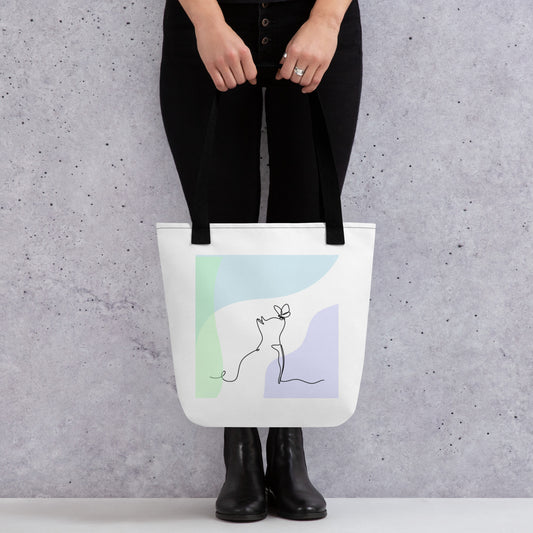 Front View of a tote bag with a design of a cat and butterfly outline. Black Handle.