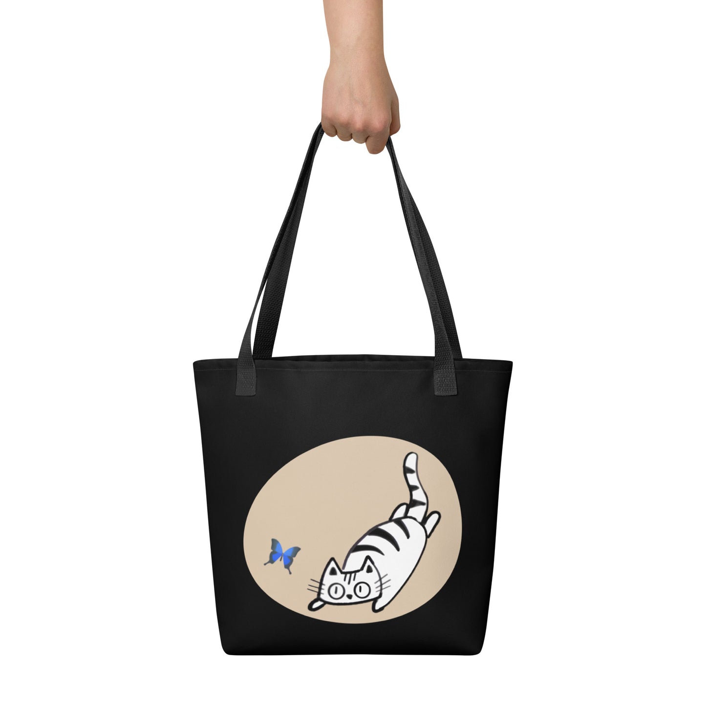 Front View of a tote bag with a design of a cat chasing a butterfly. Black Handle.