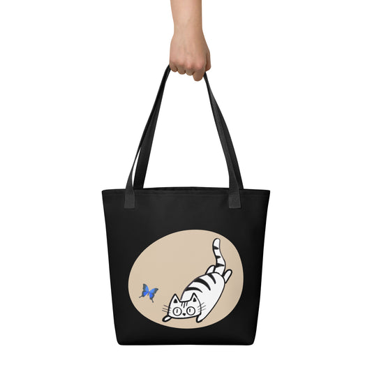 Front View of a tote bag with a design of a cat chasing a butterfly. Black Handle.