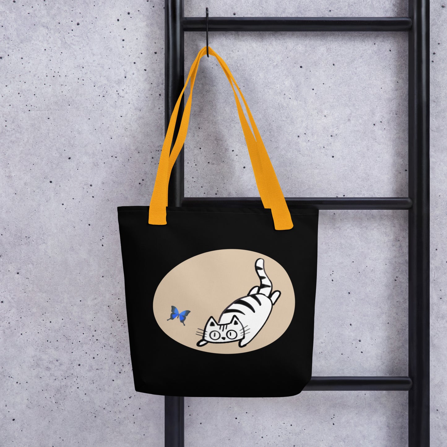Front View of a tote bag with a design of a cat chasing a butterfly. Yellow Handle.