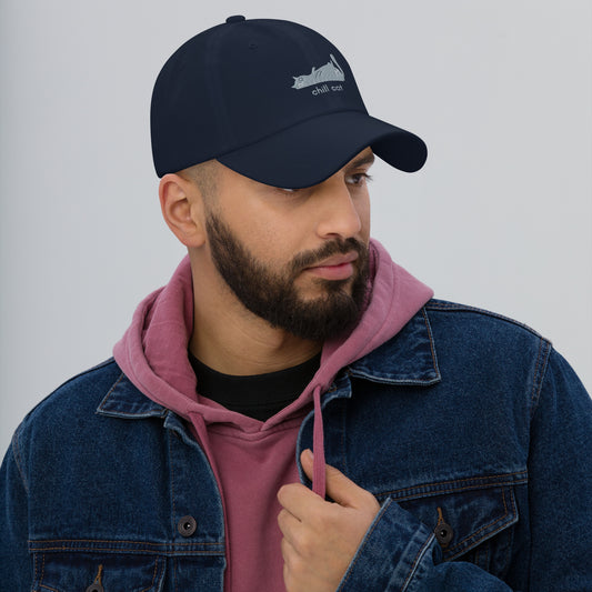 Man wearing a navy cap with a design of a cat lying down and the words "Chill Cat".