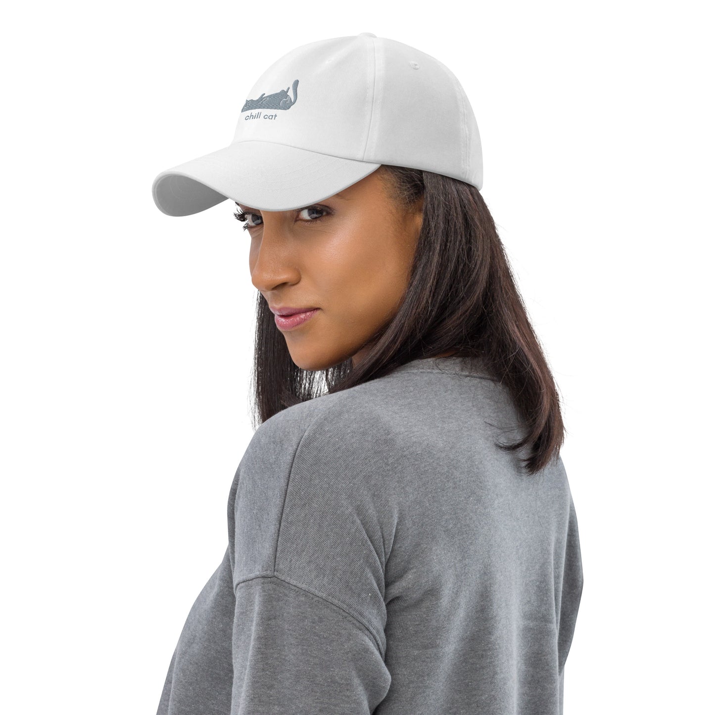 Woman wearing a white cap with a design of a cat lying down and the words "Chill Cat".