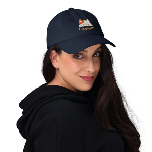 Woman wearing a navy cap with a design of a cat's face and the words 'Lucky Charm'.