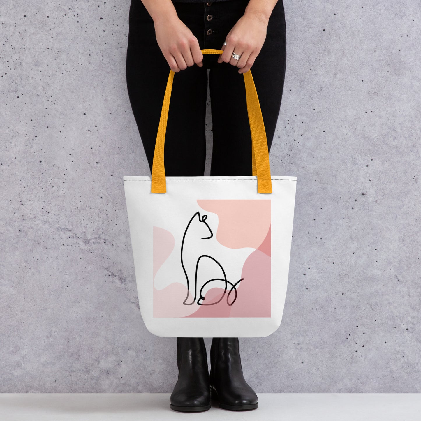 Front View of a tote bag with a design of a sitting cat outline. Yellow Handle.