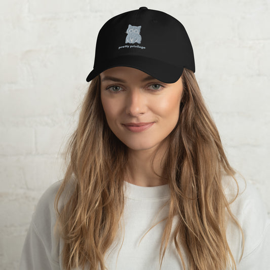 Woman wearing a black cap with a design of a sitting cat and the words "Pretty Privilege".