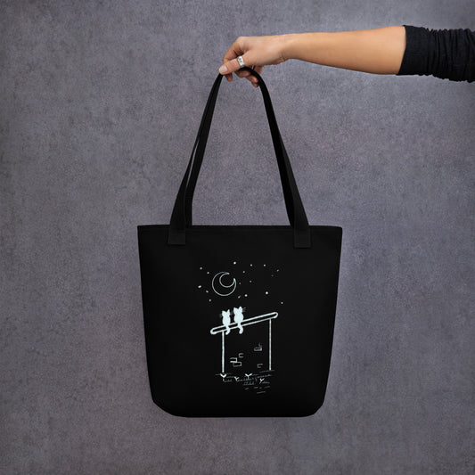 Front View of a black tote bag with a design of two stargazing cats. Black Handle.